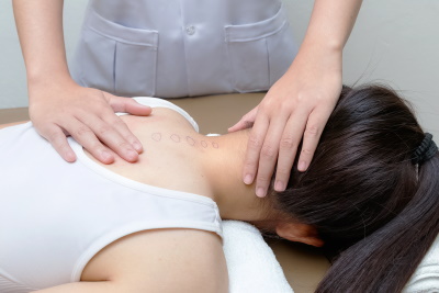 A Chiropractor has their left hand on the patient's head and their right hand on the patients back, while performing an adjustment, Viral Family Chiropractic, Treatment of Neck and Back Pain, Mt. Pleasant, SC.