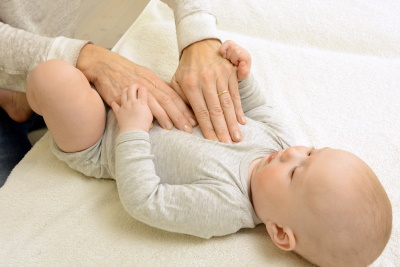 A baby is lying down on the exam table, while a pediatric chiropractor has their hands placed on the baby's chest, Vital Family Chiropractic, Pediatric Chiropractors, Mount Pleasant, S.C.
